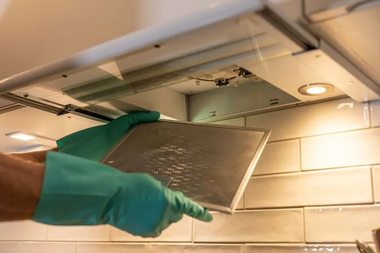 Gloved professional cleaning a hood filter